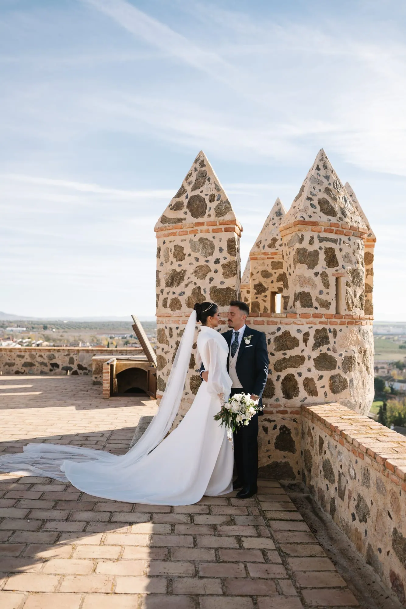 Antonio y Ainara entre las torres del Castillo de Guadamur, con la vega de Toledo al fondo