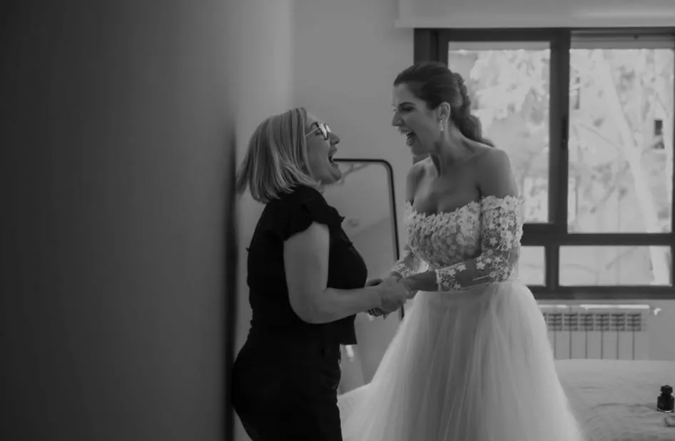 Mercedes y una novia riéndose a carcajadas, cogidas de las manos, antes de la boda