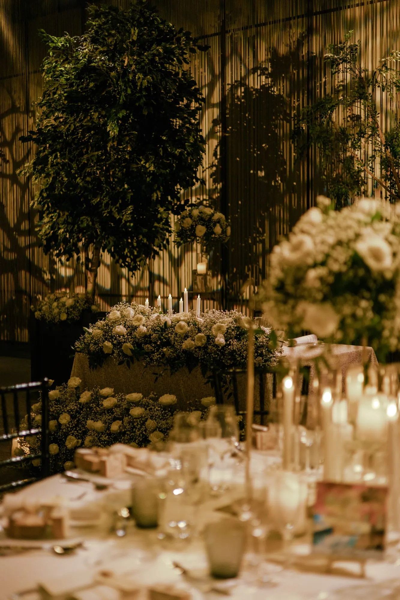Banquete al aire libre bajo los árboles, iluminado con velas