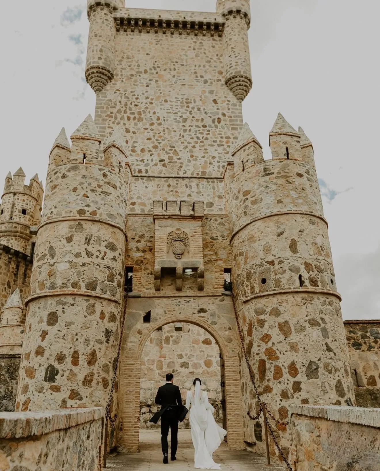 Los novios de espaldas bajo la puerta del Castillo de Guadamur